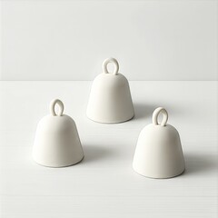 Three white ceramic bells on neutral background