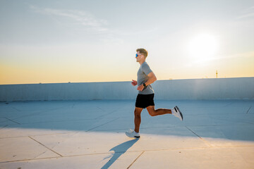 Energetic runner enjoying the sunset on a rooftop in the evening glow