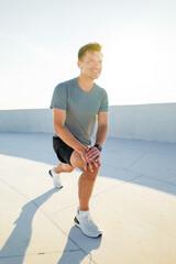 Energetic young man stretches during a sunny morning workout on a rooftop