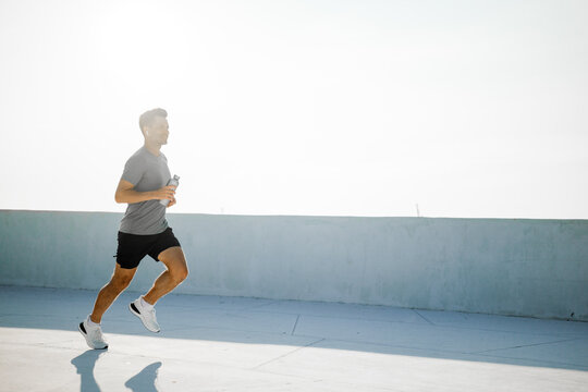 Jogging under the bright sun with a refreshing drink in hand on a peaceful morning