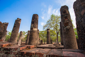 Ancient stone pillars, columns at Sukhothai province Thailand, stand tall against a clear blue sky. Weathered columns exhibit showcasing historical architecture.