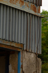 The structure features a rusty, aging metal roof complemented by a charming blue door that adds an...
