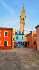 una piazza su cui si affacciano un campanile e le carattersitiche case colorate nel pittoresco...