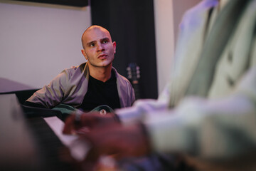 A musician is deeply focused while playing guitar in a recording studio setup. The environment...