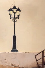 An antique street lantern is artistically painted on the wall of a house, blending vintage charm with creative urban expression