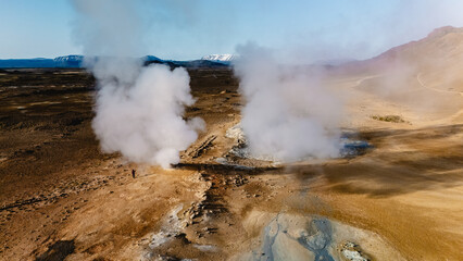 Expansive Hverir geothermal area in Iceland reveals steaming vents rising from the earth, surrounded by a unique, arid landscape. The distant mountains add to the stunning natural beauty.