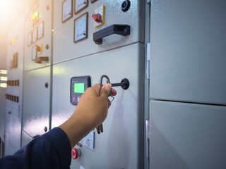 Electrical engineering is checking the electrical control panel by opening the panel cabinet lock.