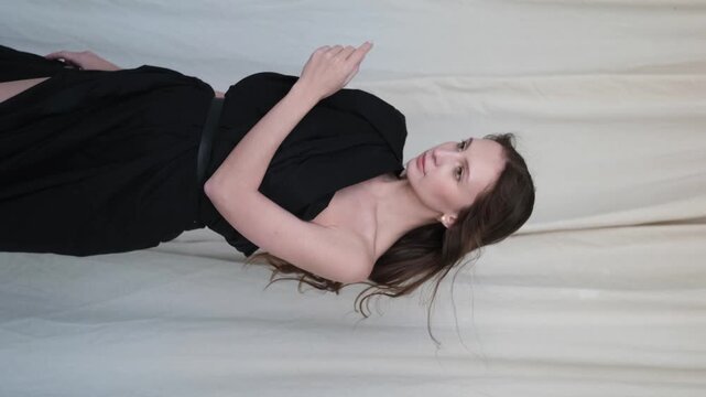 Portrait of a beautiful brunette with long hair on a fabric background in the studio. Beautiful natural woman posing for the camera