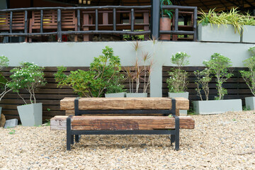 Rustic wooden bench on gravel ground, surrounded by potted plants. Background features a building...