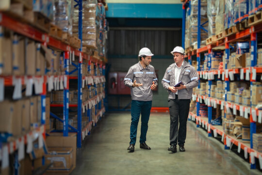 Two male warehouse workers collaborating near shelves. Relevant for teamwork content, warehouse management systems, and industrial consulting.