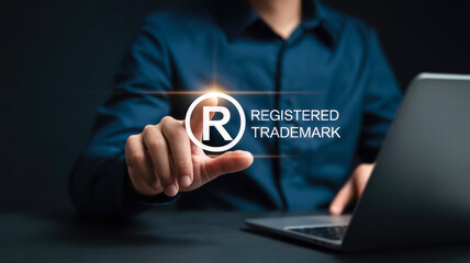 A persons finger touches a glowing registered trademark symbol and text, emphasizing brand protection and intellectual property in the digital age