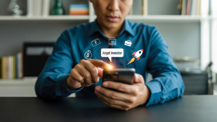 A man uses a smartphone displaying angel investor and a rocket icon, representing startup funding and business growth opportunities
