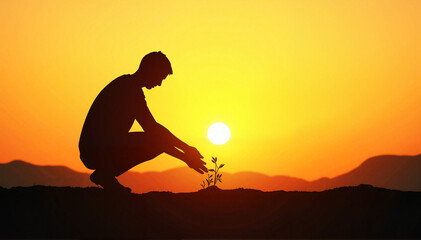 Silhouette of a man planting a seed in the soil with hope for the future.