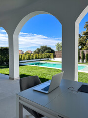Modern workspace featuring a laptop on a desk with glasses, set in a bright outdoor area with...