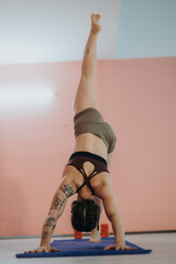 A woman performs a handstand yoga pose on a mat, showcasing balance and flexibility in a serene...