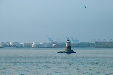 Robbins Reef Lighthouse y al fondo edificios industriales del puerto de New Jersey. Faro situado en...
