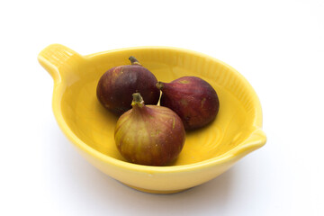 Three figs in a small saucer on a white background. The antioxidants in figs, such as polyphenols and flavonoids, can help protect against cell damage caused by free radicals.