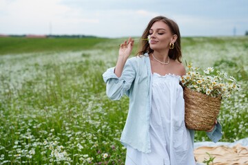Young woman holding chamomile basket in green field,healing herbs gathered with care,healing...