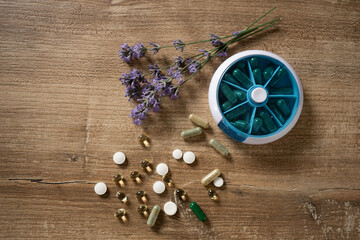 Natural health remedies displayed with colorful capsules and calming lavender on a rustic wooden...