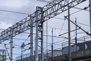 Intricate railway electrical catenary system with a complex network of metal structures and wires, supporting modern public transport infrastructure