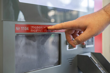 Hand reads Braille text Nr 1104 on a self-service machine, promoting accessibility and inclusivity...