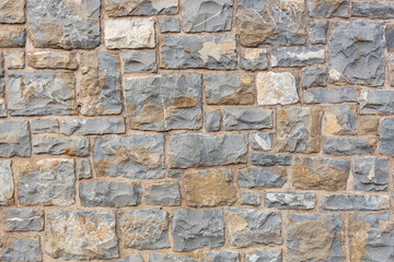Textured stone wall with varied gray and beige bricks for background