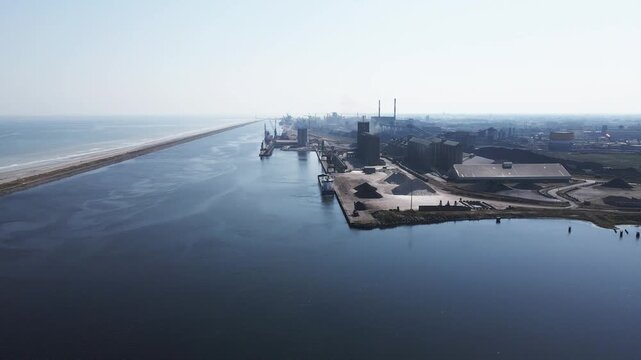 Aerial view of Dunkirk's industrial port, a landscape of docks, cranes, and grain elevators under a hazy sky, Dunkirk, Hauts-de-France, France.