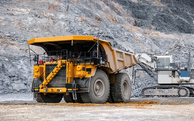 Heavy Mining Dump Truck with gold ore and Excavator at Open-Pit Mine © Parilov