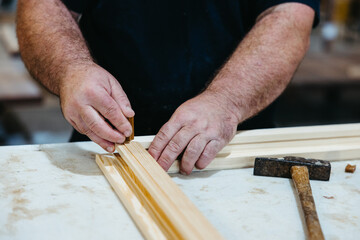 Close-up of worker inserting wooden dowels to join window frame pieces