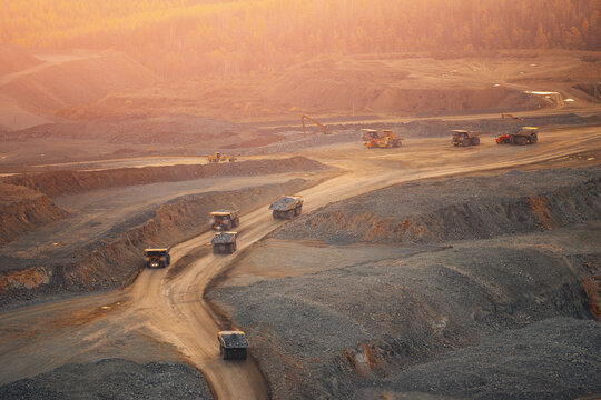 Heavy Machinery in Open Pit Mine at Sunset. Industrial Landscape and Mineral Extraction in Quarry gold, copper and iron ore.