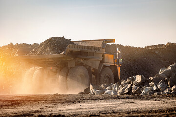 Massive Mining Dump Truck Moving Earth in Dusty Open Pit Quarry During Sunset © Parilov
