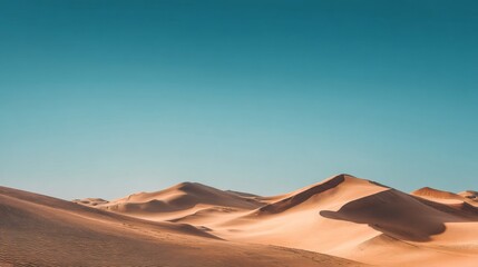 Majestic sand dunes under clear blue sky in tranquil desert landscape