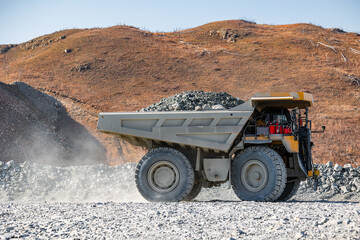 Obraz premium Open pit mine industry, big yellow mining truck for gold ore.