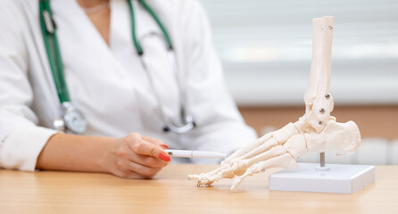 Female medical professional demonstrating human foot anatomy with skeletal model