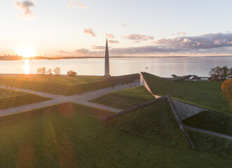 Aerial view of the Estonian War of Independence Victory Column piercing the skyline at sunset, set against the vast sea horizon, Tallinn, Harju County, Estonia.