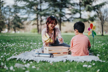 A Filipino mother enjoys a picnic in the park with her child, sharing snacks and laughter. The...