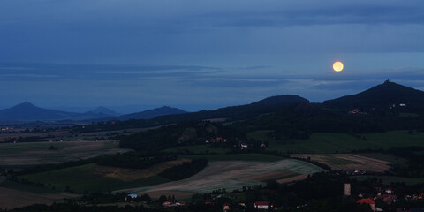 Full Moonset Behind Dark Hill Ridge Silhouettes at Blue Hour