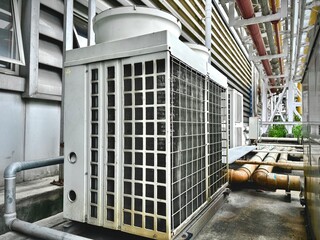 modern building in the city. Industrial HVAC outdoor units with visible copper piping and weathered surfaces, essential for factory climate control and cooling systems in heavy-duty operations.