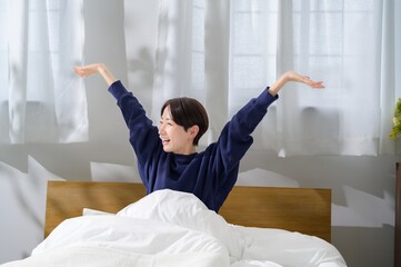 朝のベッドでリラックスする日本人女性