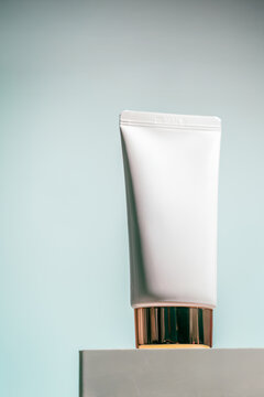Cream jar with gold lid placed on a white podium against a pastel blue background. Minimal skincare product shot for beauty branding, cosmetic ads, and clean product mockups