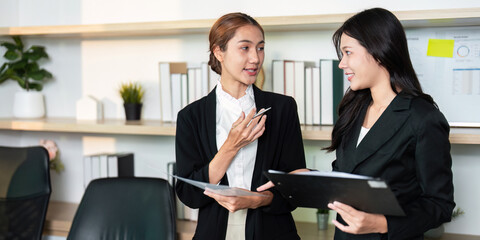 Effective Communication. Two women discussing business strategies in a modern office setting.