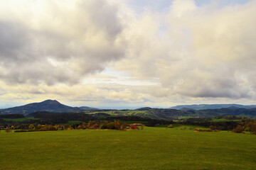Hazy Meadow Landscape with Hills Under Cloud Cover