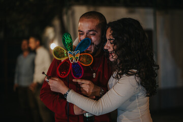 Cheerful couple shares a joyful moment while holding a vibrant pinwheel, radiating happiness and...