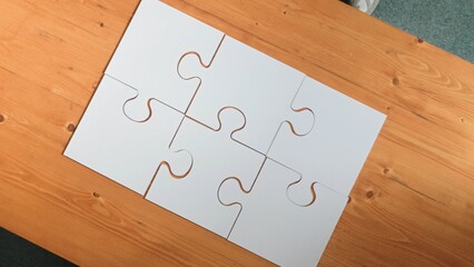 Top down aerial view of business man gathering last piece of jigsaw to complete puzzle. Group of...