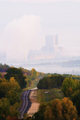 Misty Road Through Autumn Trees Towards Coal Power Plant in Foggy Background