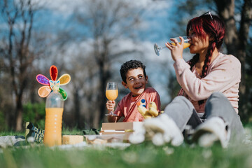 A joyful scene of an Asian mother and her child enjoying a relaxing picnic amidst nature, sipping...