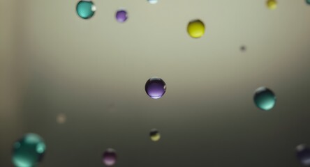 Close-up view of floating colorful spheres in a neutral gray background with selective focus and bokeh effects. Variety of colors include purple teal and yellow adding depth and visual interest.