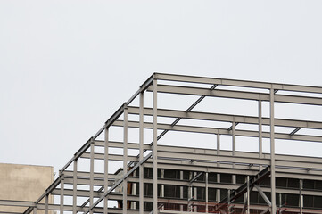 Fototapeta premium concrete building and metal beam frame during construction against grey sky
