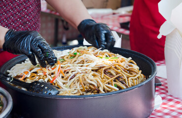 Close-up of traditional Asian glass noodles (funchoza) stir-fried with fresh vegetables such as...