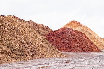 Mountains of wood chips against a gray sky close-up